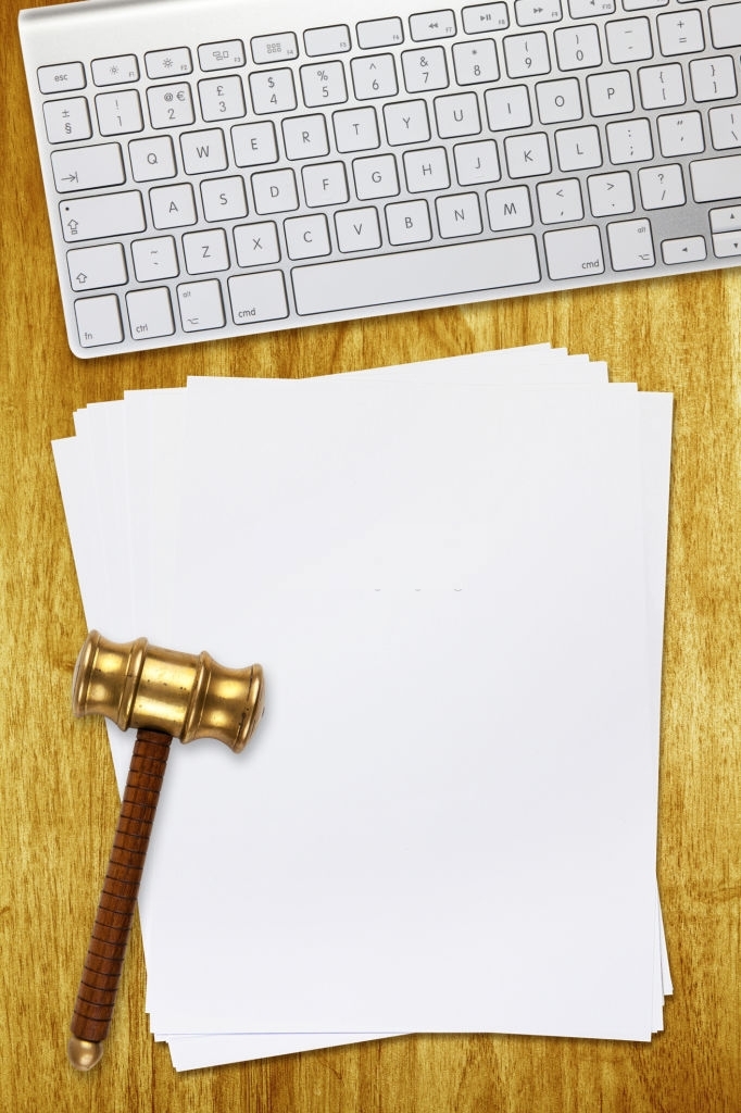 Overhead view of gavel on blank paper next to keyboard